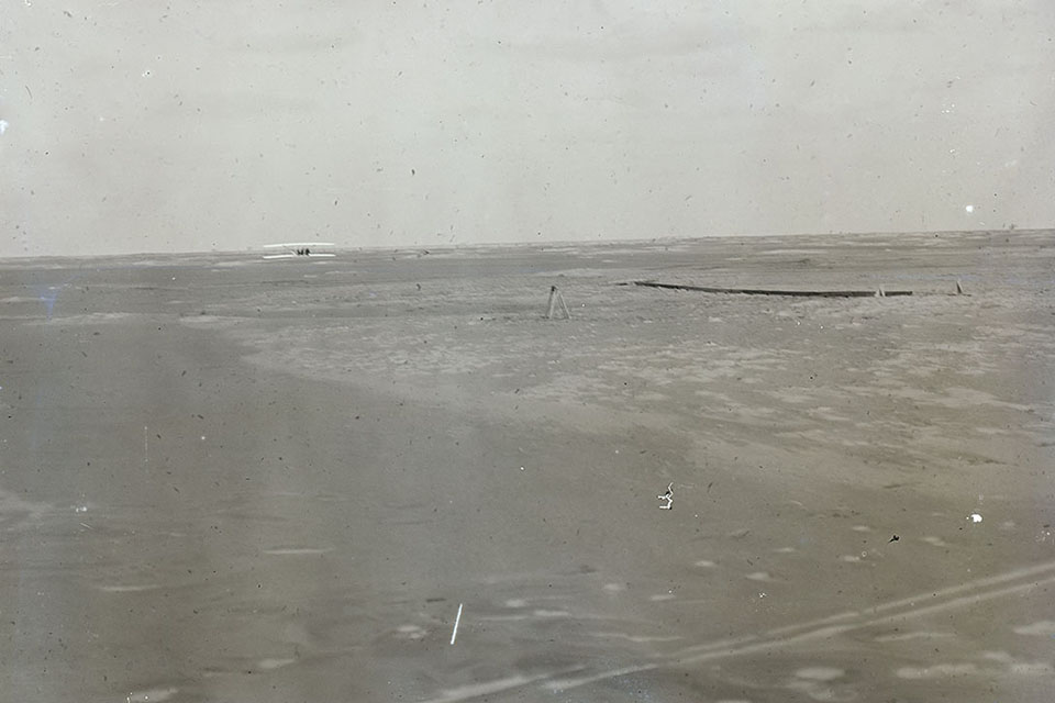 The only picture of the last of the Wrights' four flights on December 17, 1903, shows the Flyer about 17 seconds into the flight, approximately 250 feet from the end of the launching track at an altitude of about 10 feet, with about another 600 feet and 42 seconds yet to go. (Library of Congress)