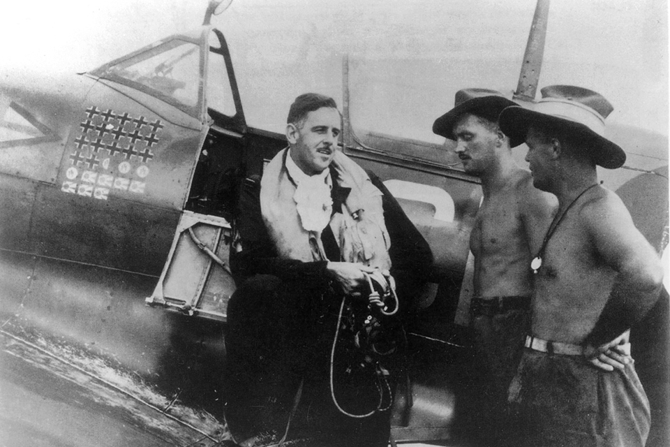 Group Captain Caldwell, commanding officer of No. 80 Fighter Wing, talks with his ground crew, Aircraftmen W.V. Flynn and Lac J. Miller, at the unit's base in the Netherlands East Indies. (AWM OG2000)