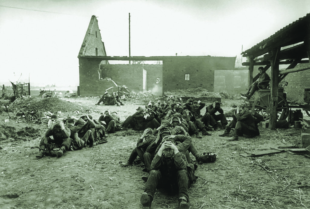German soldiers captured by American paratroopers on March 24, 1945, crouch in an improvised POW enclosure in Wesel. (© Robert Capa © International Center of Photography/Magnum photos)