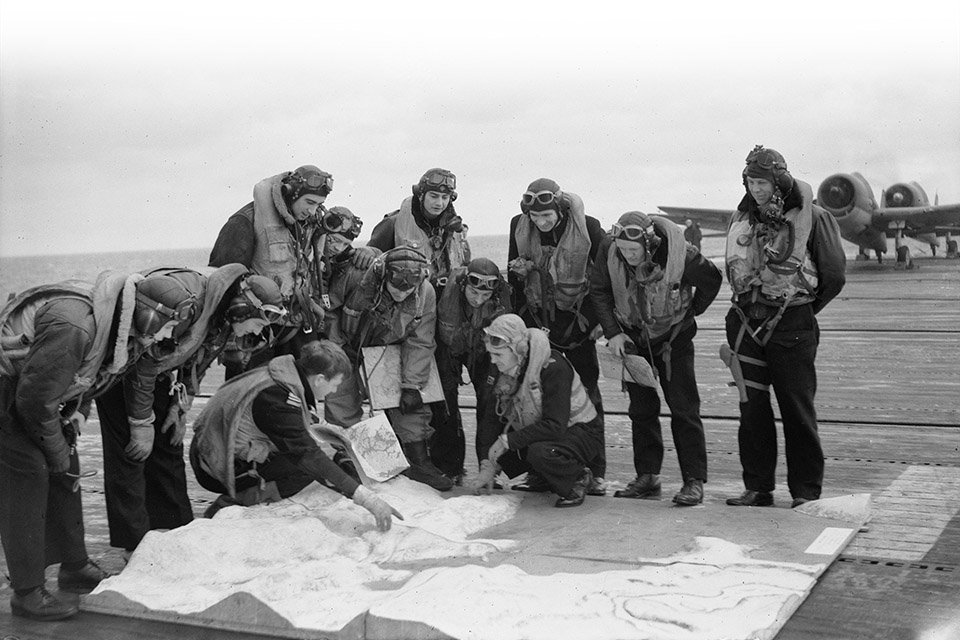 Hellcat pilots aboard Emperor study maps and a model of the Norwegian fjord prior to joining the strike on Tirpitz. (IWM A22651)