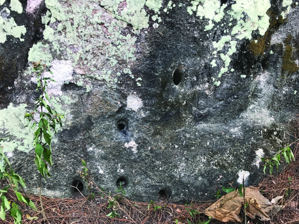 Wartime ordnance still pockmarks a rock at the base of Hill 208. (William R. Coulson)