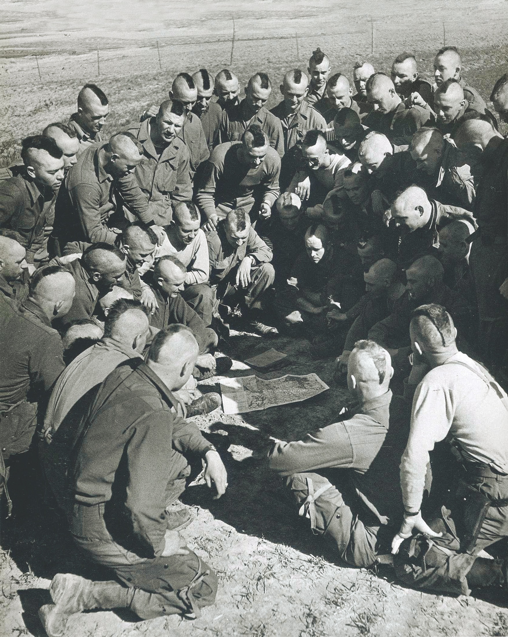 Sporting Mohawk haircuts for luck and esprit de corps, paratroopers get a last-minute briefing before gearing up. (Robert Capa/International Center of Photography/Magnum Photos)