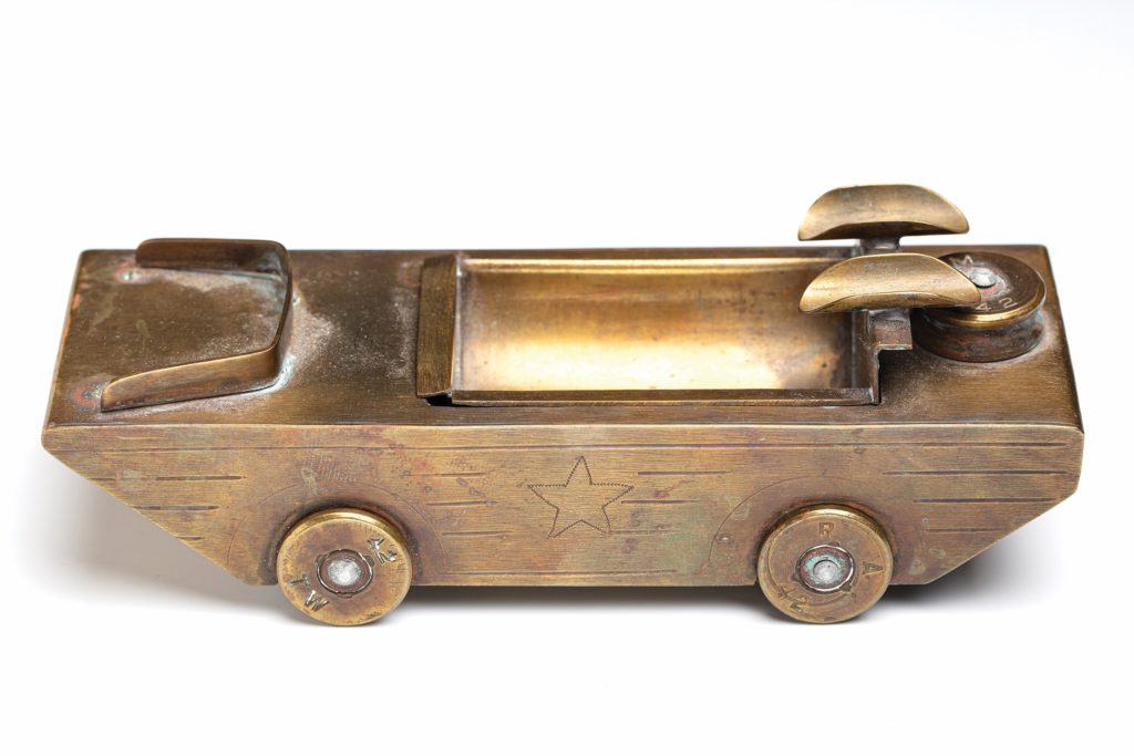 SMOKE ON THE WATER: Ashtrays were a universally popular form of trench art: “Everybody smoked,” Czekanski says. Typically made from artillery shells, few repositories were as skillfully crafted as the one above, by Technician Fifth Grade Andrew Church of the 26th Infantry Division. Constructed to resemble an amphibious jeep, it features two cigarette rests and realistic detailing.