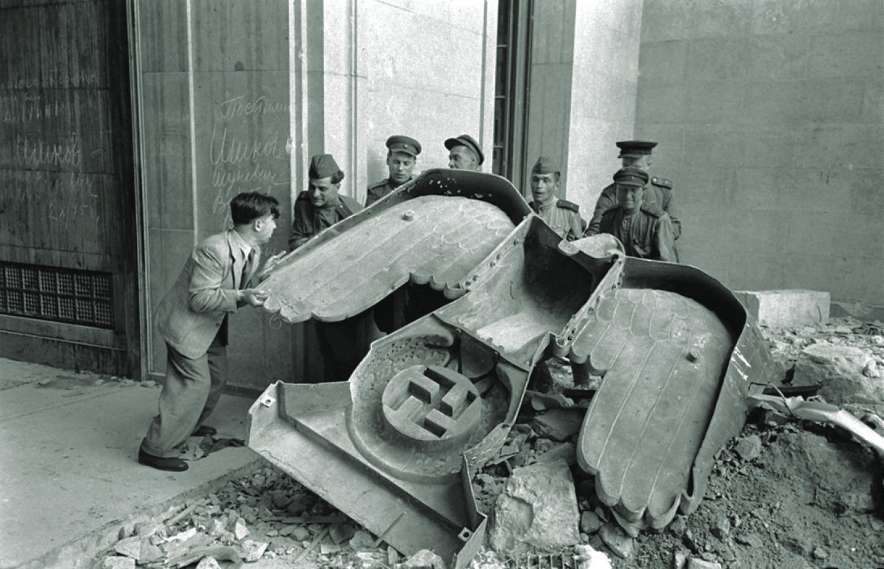 Russian troops handle a fallen Nazi Party eagle amid debris at the Reich Chancellery in Berlin. The Cold War struggle for Germany and the rest of Europe was just beginning. / Alamy