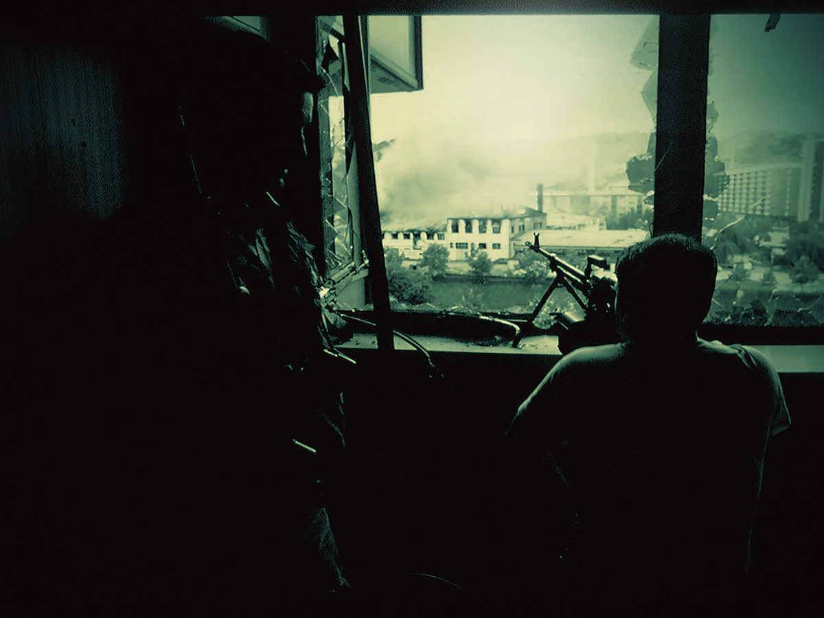 Photo of a sniper scaning for a target on the streets of embattled Sarajevo at the outset of the 1992–95 Bosnian War. The breakup of Yugoslavia was accompanied by ethnic strife, urban warfare and civilian displacement.