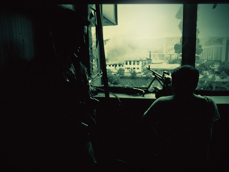 Photo of a sniper scaning for a target on the streets of embattled Sarajevo at the outset of the 1992–95 Bosnian War. The breakup of Yugoslavia was accompanied by ethnic strife, urban warfare and civilian displacement.