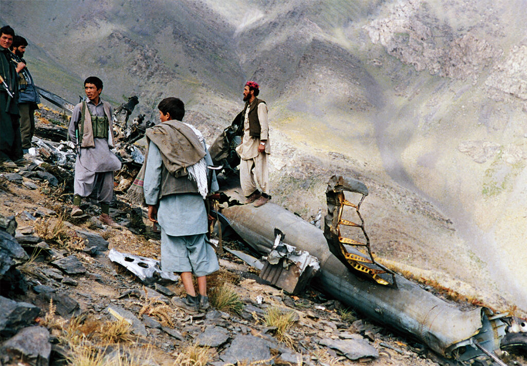 Photo of Mujahidin (mujahideen) of the Harakat-e Islami Party of Afghanistan standing beside the debris of an helicopter they had shot down with a stinger missile in sanglakh valley, Maiden Province (west of kabul) in afghanistan at the end of June.