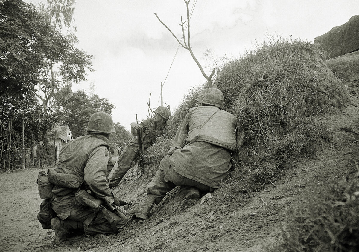 Photo of three American advisers, who had to abandon the Quang Tri base camp 19 miles south of the DMZ in face of enemy offensive, crouch in ditch for protection against incoming North Vietnamese Artillery. The soldiers were making their way to nearby city of Quang tri, South Vietnam on April 3, 1972.