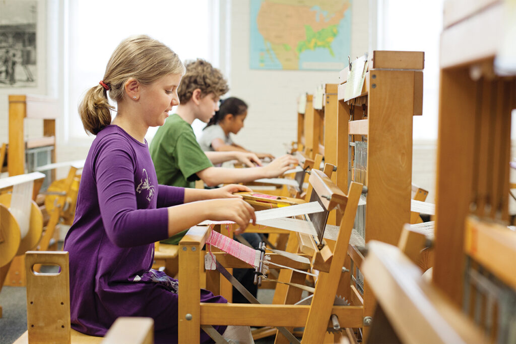 Photo of Children using weaving looms, while visiting Lowell National Historical Park.