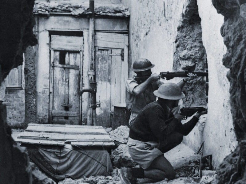 Photo showing The long awaited all out Arab attack on the Jews has begun according to widespread reports of violence and attacks from the Holy Land. Here we see two members of the Palmach, the striking force of the Haganah, as they fired through a hole in a wall while training recently for city fighting. The Haganah, once illegal, is now working openly and has registered all men and women between the ages of 17 and 35. Actually, those under 25 only are called in the draft. The main problem has been to keep too many men and women over 35 from trying to serve when they are of more use in vital civilian jobs. The Defense Army organized 30 years ago has since grown to a full and efficient fighting force capable of coping with the dangerous situation which now faces it.