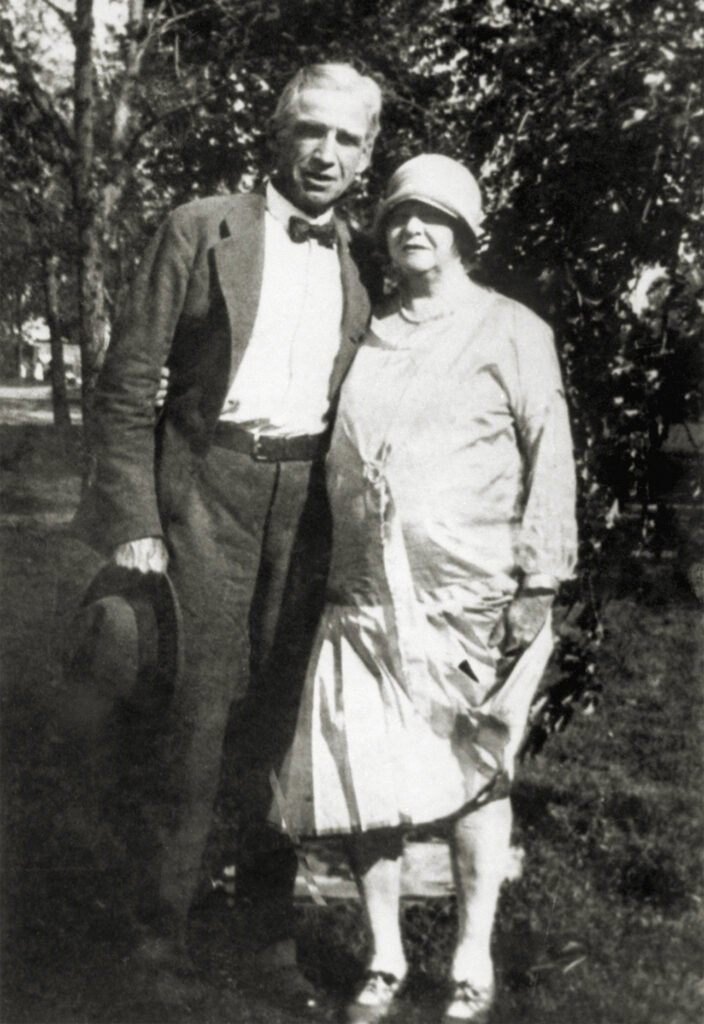 This photo shows Mrs. Arrie Barker, also known as Kate, 60-year-old mother of the four Barker brothers, all outlaws, slain with her son Fred in a gun battle in Florida, Jan. 16. Shown with her in the photograph is Arthur W. Dunlop, "Ma's" close freind, when the Barkers lived in their hideout near Thayer, MO. They are shown standing in what appears to be a garden.