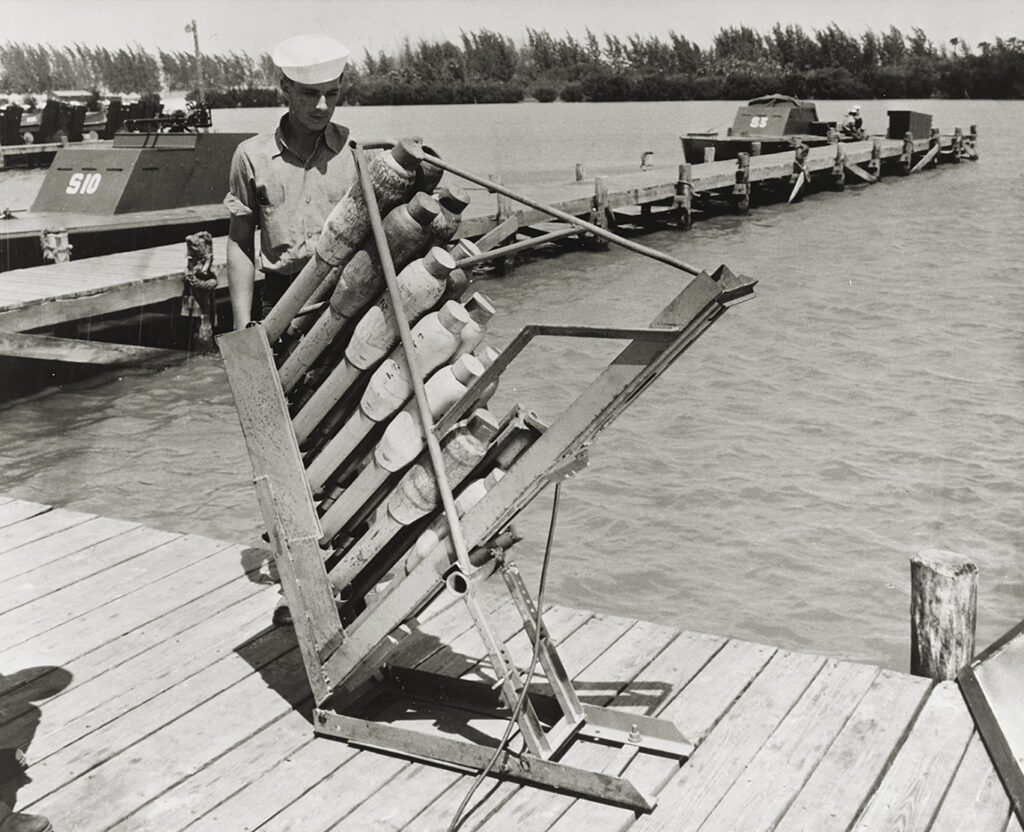 Photo of, mounted athwartships between the bow gun and the forward twin Bofors were 10 Mark 7 rocket launchers like that at top at a Florida training base. Welded to the deck at a fixed 45-degree angle in two groups of five, each launcher carried a dozen 4.5-inch fin-stabilized rockets, totaling 120 rockets per ship. Each rocket delivered a TNT payload up to 11,000 yards downrange.